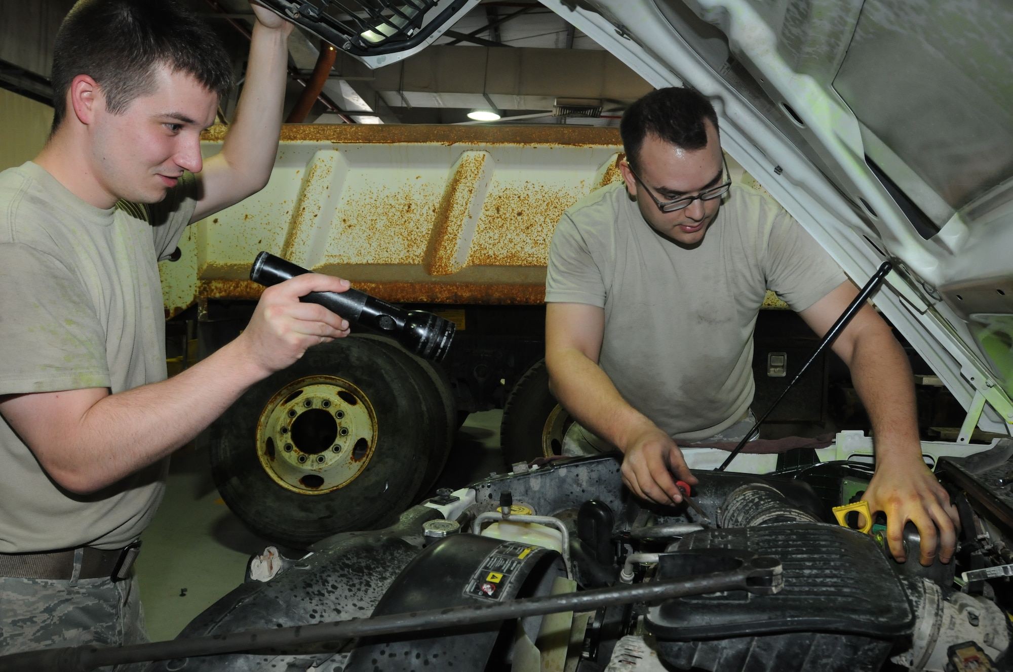 SOUTHWEST ASIA - U.S. Air Force Senior Airman Cody Farris, 380th Expeditionary Logistics Readiness Squadron vehicular and vehicle equipment maintenance journeyman, holds a flashlight for Senior Airman Anthony Sackreiter, 380th ELRS vehicular and vehicle equipment maintenance journeyman, as he works on removing a Dodge Dakota truck's heating, ventilation and air conditioning unit Nov. 28, 2012. Farris, a Manchester, Tenn., native is deployed from Eielson Air Force Base, Alaska, and Sackreither is a Rapid City, S.D., native deployed from McChord AFB, Wash. (U.S. Air Force photo/Tech. Sgt. Amanda Savannah)