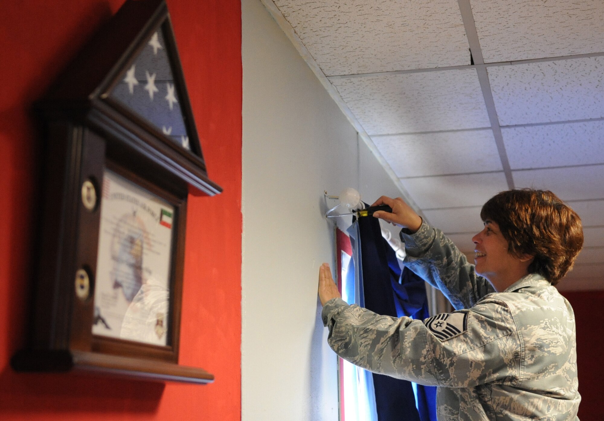 SOUTHWEST ASIA – Master Sgt. Barbara Paravola-Roschal, 386th Expeditionary Force Support Squadron project manager, sets up the drapes in the newly-renovated morale trailer in Commando Village here Nov. 28. Paravola was the fitness center manager in which she was responsible for her Airmen and oversees operations for three fitness facilities and the base pool.  She recently renovated the morale trailer—painting the walls, replacing the old furniture, making the trailer home-like. Paravola is the 386th Air Expeditionary Wing Rock Solid Warrior. (U.S. Air Force photo/Staff Sgt. Alexandra M. Boutte)