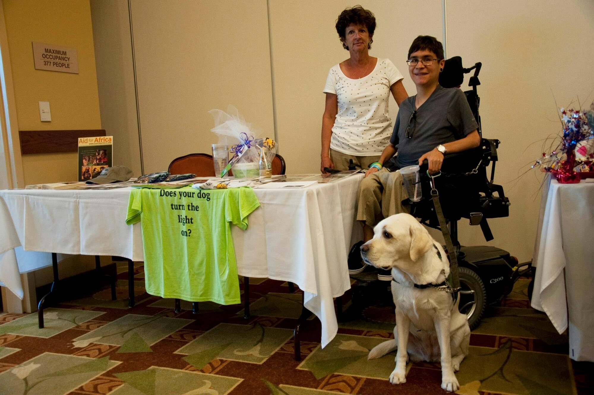 Cody and Nina Cobia, representatives of an organization that provides service dogs to veterans, pose in front of their booth with their dog, Toni, during the Combined Federal Campaign kickoff at the Soundside Club at Hurlburt Field, Fla., Sept. 25, 2012. Toni is a service dog that aids physically disabled people and veterans with daily tasks such as picking up items, turning on lights and opening doors. (U.S. Air Force Photo/Airman 1st Class Benjamin D. Kim)