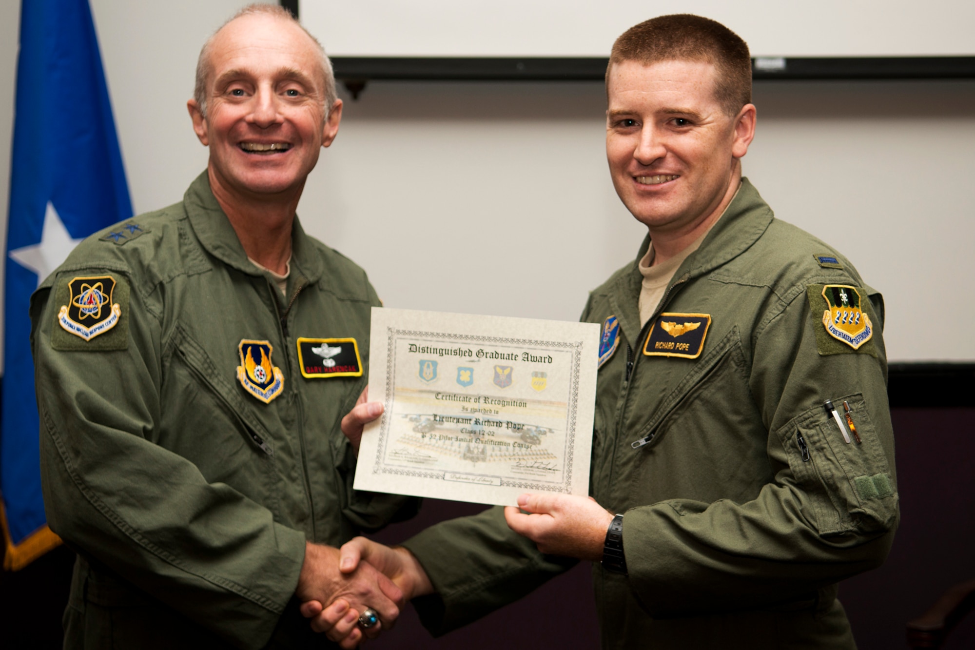 U.S. Air Force Maj. Gen. Garrett Harencak, Air Force Nuclear Weapons Center commander, presents the Copilot Distinguished Graduate award to 1st Lt. Richard Pope during a B-52 Formal Training Unit Graduation ceremony, Sept. 28, 2012, Barksdale Air Force Base, La. The Distinguished Graduate Award is a culmination of academic tests, flight evaluations, officership, attitude and professional bearing, and the winner is selected by having demonstrated training and performance that was consistently and clearly above their peers. (U.S. Air Force photo by Master Sgt. Greg Steele/Released)