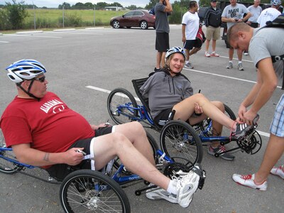 Former Staff Sgt. Claude Owens and retired Senior Airman Ramina Oraha prepare for a recumbent bike ride along the flightline at Joint Base San Antonio-Randolph, Texas. Assisting Oraha is her brother, Mike. Cycling was one of the sports offered during an Air Force Adaptive Sports Program camp Sept. 14 and 15. (U.S. Air Force photo/Tammy Cournoyer)