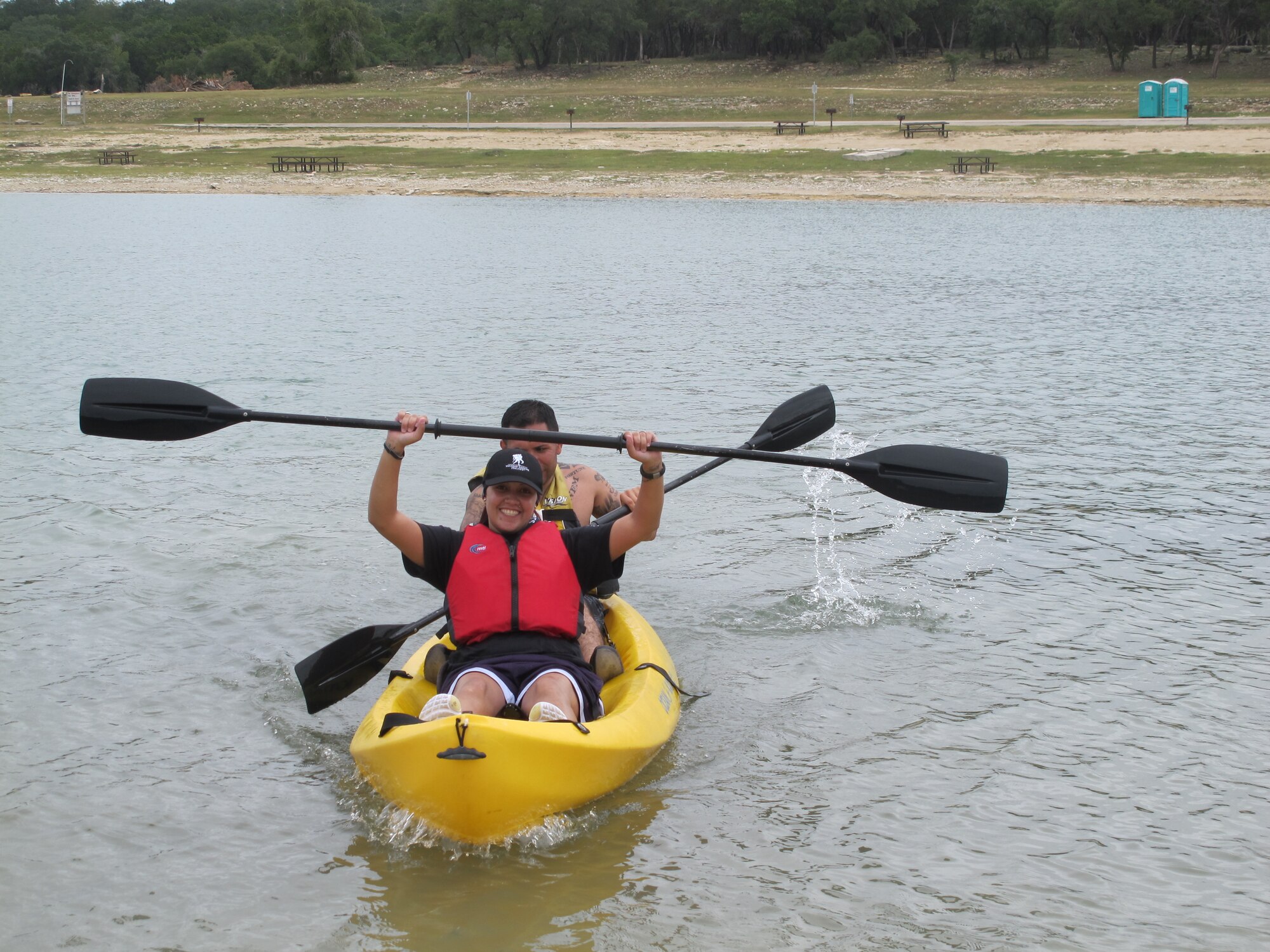 Retired Staff Sgt. Zuleika Cruz-Pereira raises her paddle in victory after completing the kayak course at Canyon Lake during an Air Force Adaptive Sports Program camp Sept. 15, 2012. Joining Cruz-Pereira is Tech. Sgt. Hugo Vitela. During camp, Air Force wounded warriors were introduced to competitive wheelchair basketball, cycling with adaptive bikes, and kayaking and water skiing around Canyon Lake.  (U.S. Air Force photo/Nicole Hart) 