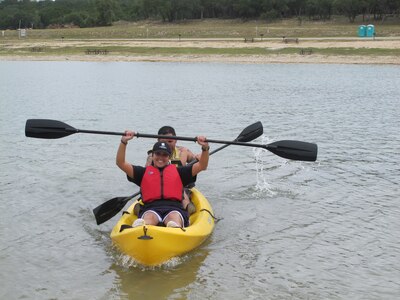 Retired Staff Sgt. Zuleika Cruz-Pereira raises her paddle in victory after completing the kayak course at Canyon Lake during an Air Force Adaptive Sports Program camp Sept. 15, 2012. Joining Cruz-Pereira is Tech. Sgt. Hugo Vitela. During camp, Air Force wounded warriors were introduced to competitive wheelchair basketball, cycling with adaptive bikes, and kayaking and water skiing around Canyon Lake.  (U.S. Air Force photo/Nicole Hart) 