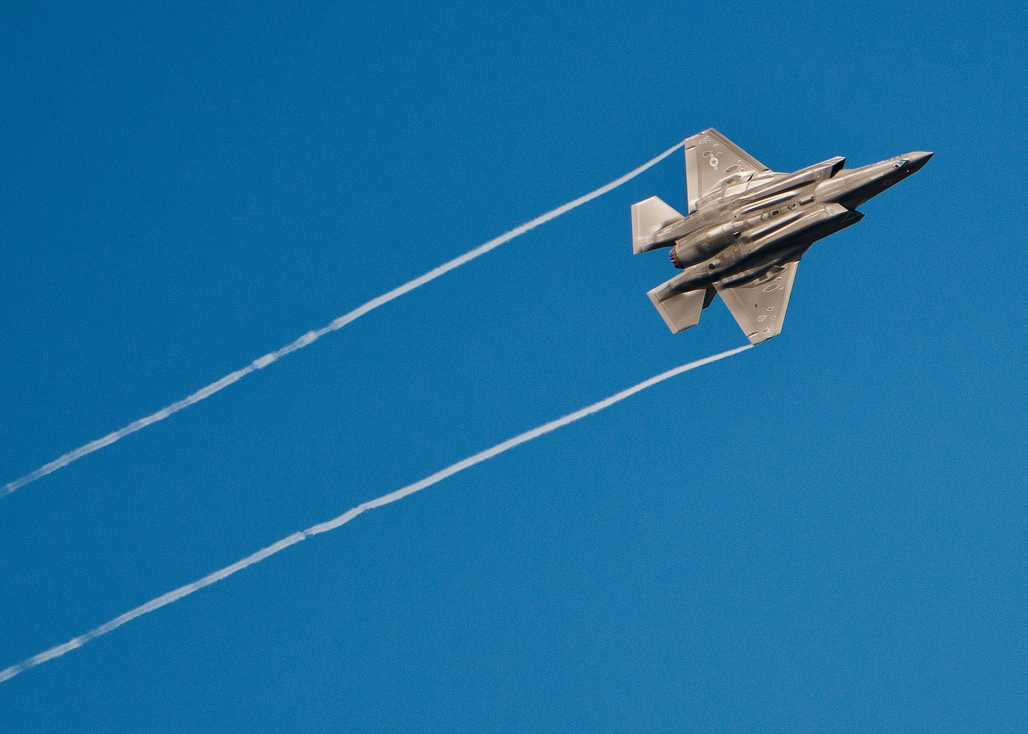An F-35 Lightning II soars leaving contrails behind it as it banks during approaches to the Eglin Air Force Base runway Sept. 28.  Both A and B variant models of the joint strike fighter fly sorties over the Emerald Coast each day.  (U.S. Air Force photo/Samuel King Jr.)