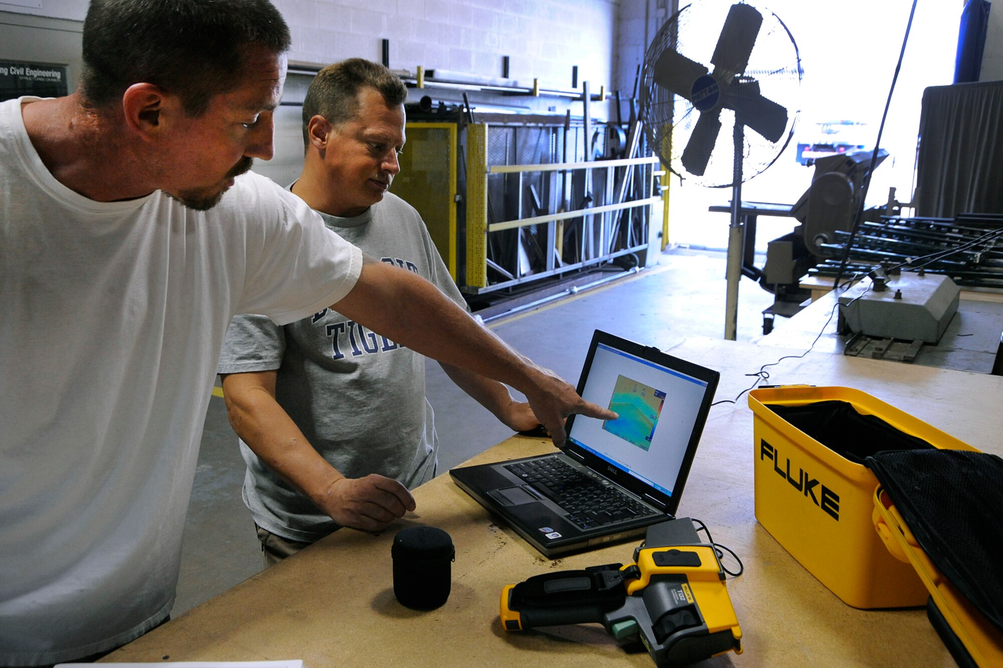 Bruce Zysk, left, and Darren Burton, a roofer and an electrician, respectively, with the 127th Civil Engineer Squadron at Selfridge Air National Guard Base, Mich., describe how they use a thermal imaging camera to develop energy saving techniques at the base. Zysk said by using the camera, he’s able to prioritize roofing repairs to help Air National Guard maximize energy conservation efforts by tackling projects that represent the most heat loss fist. (Air National Guard photo by John S. Swanson)