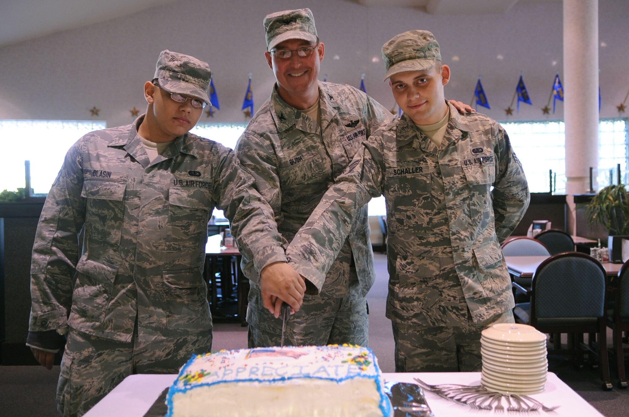 Airman 1st Class Forrest Olasin (left) and Senior Airman Jacob Schaller, both with the 319th Force Support Squadron, join Col. Timothy Bush, 319th Air Base Wing commander, in cutting the commemorative cake for the Airmen Appreciation Dinner, Sept. 26, 2012, at the Airey Dining Facility on Grand Forks Air Force Base, N.D. Members of the base senior leadership hold dinners such as this during different times of the year in order to say thanks to Airmen for all they do to get the mission done. (U.S. Air Force photo /Staff Sgt. Amanda N. Grabiec)