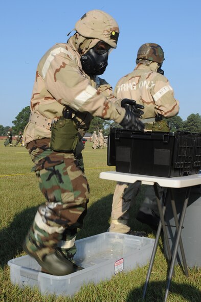 U.S. Air Force Staff Sgt. Jesus Venegas, 4th Logistics Readiness Squadron vehicle operator, cleanses his mission oriented protective posture gloves and boots during an ability to survive and operate exercise on Seymour Johnson Air Force Base, N.C., Sept. 26, 2012. Airmen used staged cleansing stations to decontaminate their gear after a simulated chemical attack. (U.S. Air Force photo/Airman 1st Class John Nieves Camacho/Released)
