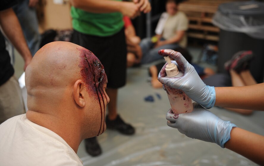 U.S. Air Force Tech. Sgt. Joie Pearcy, 23d Medical Group NCO in charge of medical readiness, applies moulage to Senior Airman Joseph Wruck, 23d Logistics Readiness Squadron air transportation apprentice, for a major accident response exercise at Moody Air Force Base, Ga., Sept. 27, 2012. The exercise was a simulated plane crash designed to prepare first-responders for a real world accidents. (U.S. Air Force photo by Airman 1st Class Olivia Dominique/Released)