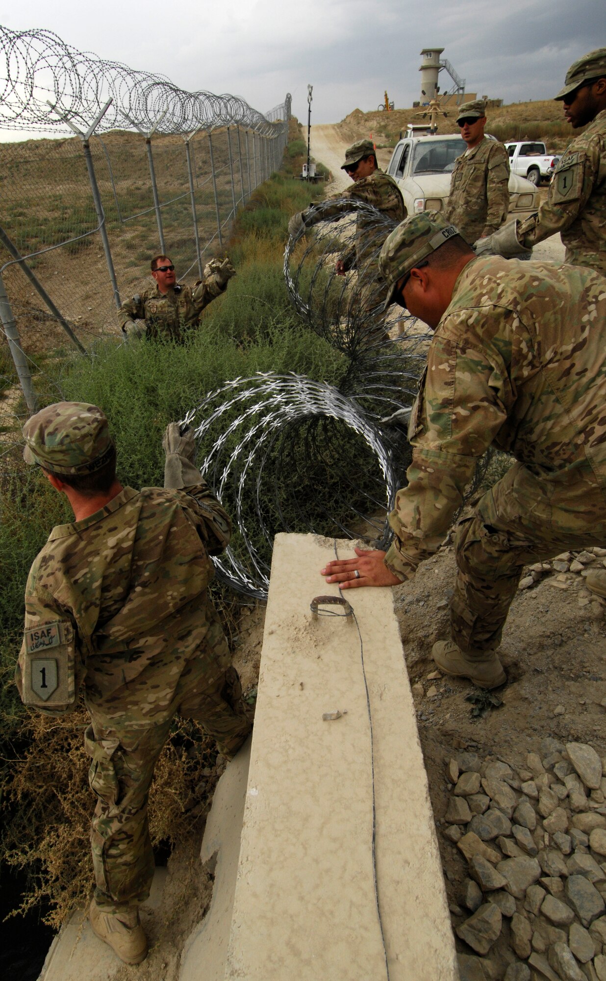 U.S. Servicemembers put up razor wire along the perimeter of Bagram Airfield Afghanistan, Sept. 26, 2012. For the past two weeks, Bagram Airmen and Soldiers volunteered together, laying razor wire along BAF’s perimeter to enhance base defenses against outside enemy threats. (U.S. Air Force photo/SSgt Jeff Nevison)