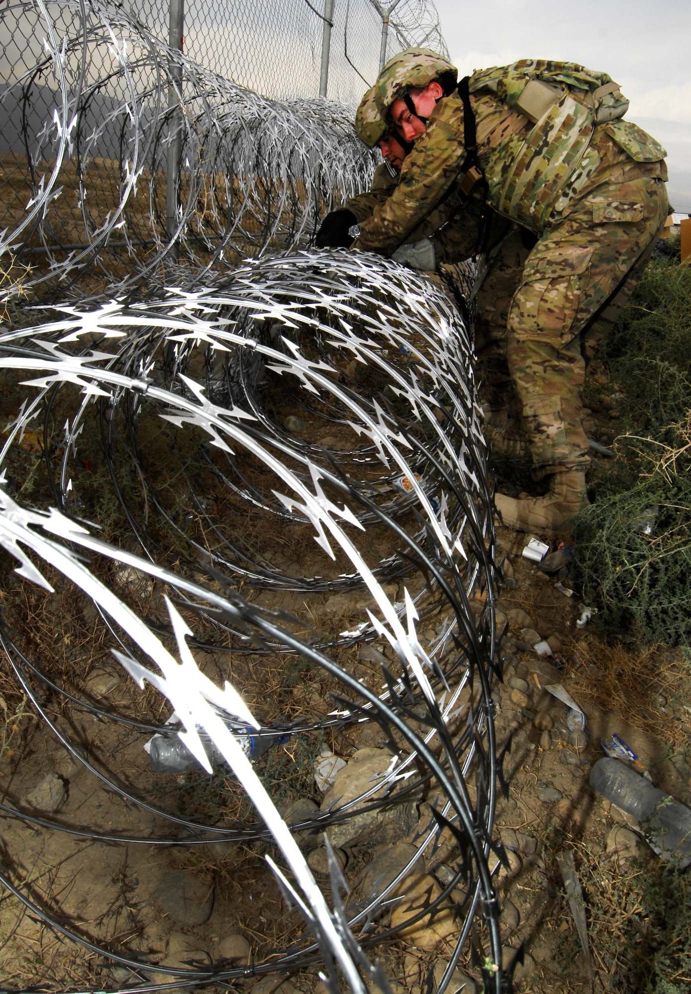 TSgt Cade Mayer, 455th Expeditionary Operations Support Squadron weather forecaster, puts up razor wire along the perimeter of Bagram Airfield Afghanistan, Sept. 26, 2012. For the past two weeks, Bagram Airmen and Soldiers volunteered together, laying razor wire along BAF’s perimeter to enhance base defenses against outside enemy threats. (U.S. Air Force photo/SSgt Jeff Nevison)