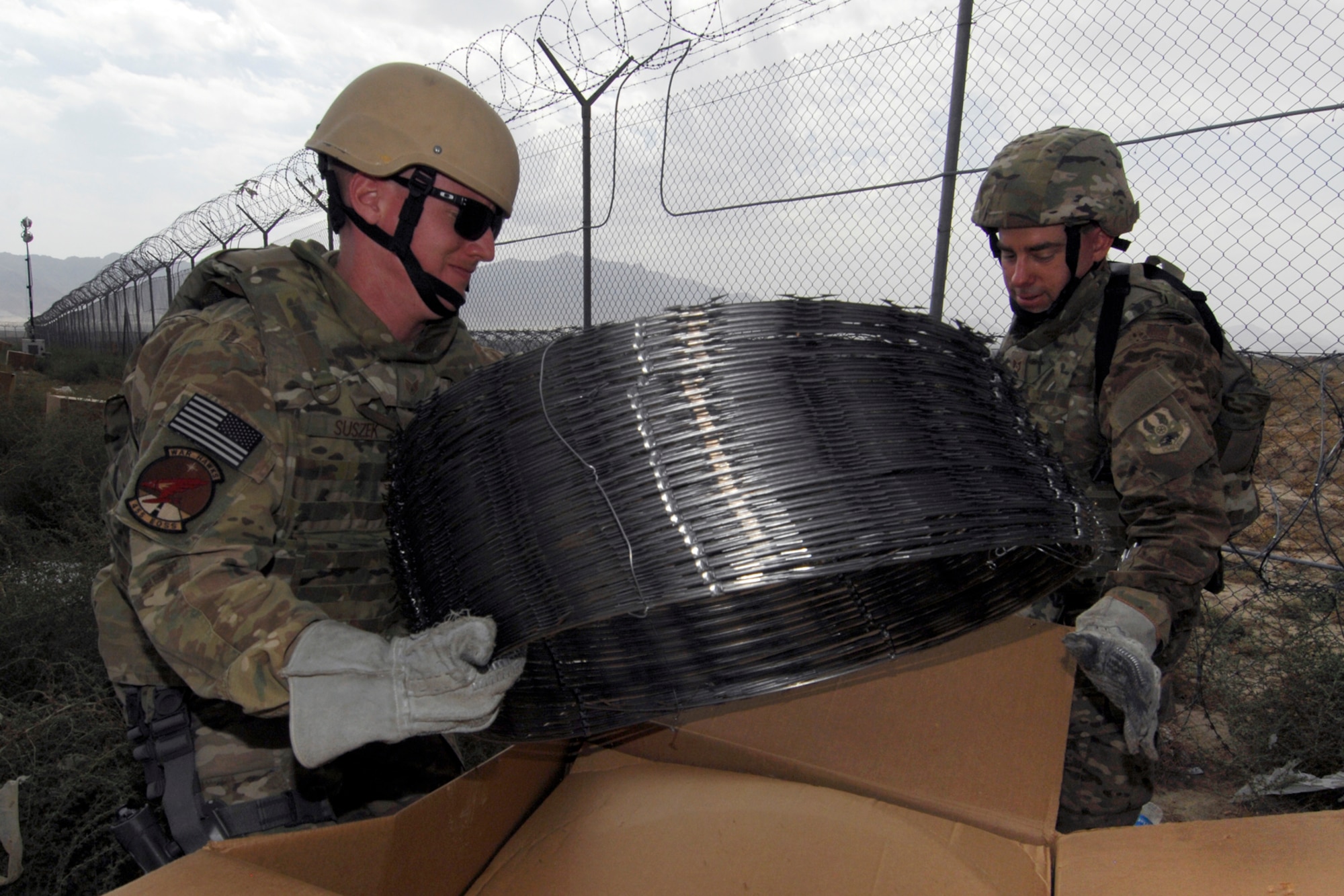 SSgt Michael Suszek (left), 455th Expeditionary Operations Support Squadron, and TSgt Cade Mayer, 455 EOSS weather forecaster, prepare to put up razor wire along the perimeter of Bagram Airfield, Afghanistan, Sept. 26, 2012. For the past two weeks, Bagram Airmen and Soldiers volunteered together, laying razor wire along BAF’s perimeter to enhance base defenses against outside enemy threats. (U.S. Air Force photo/SSgt Jeff Nevison)