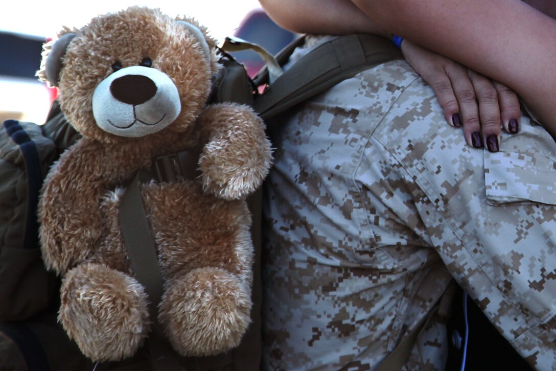 A Marine hugs his wife during a 1st Battalion, 7th Marine Regiment, homecoming event Sept. 15, 2012 at Del Valle Field. He secured a teddy bear to his pack to give his son after 1/7’s seven-month long deployment to Helmand province, Afghanistan.