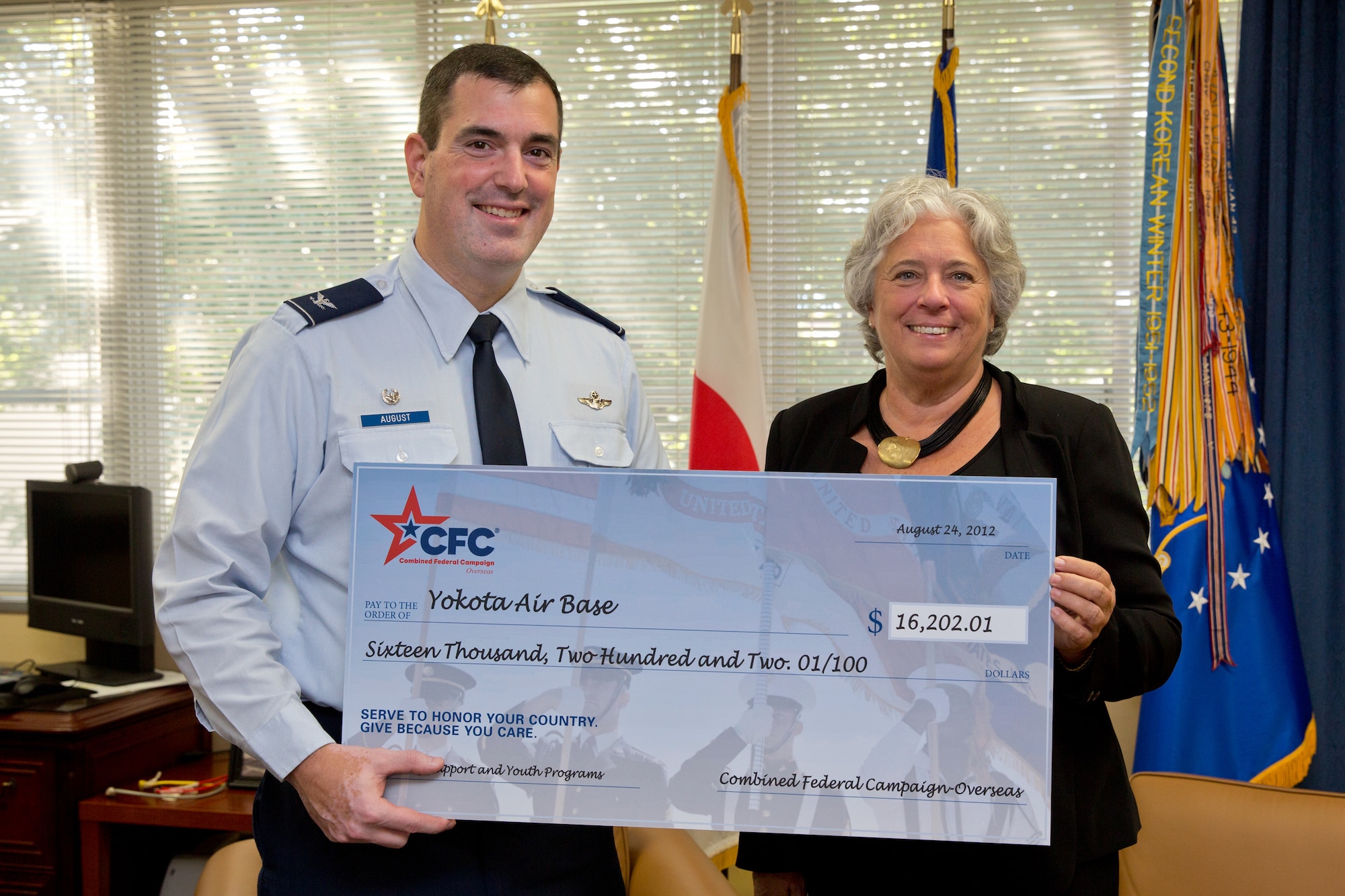 YOKOTA AIR BASE, Japan -- Renee Acosta, president and CEO of Global Impact, the managing company of Combined Federal Campaign-Overseas, presents Col. Mark August, 374th Airlift Wing commander, a $16,202 check for family support and youth programs, Oct. 1, 2012, at Yokota Air Base, Japan. More than 1,000 service members and federal employees from Yokota donated more than $256,000 to the CFC-O in 2011. (U.S. Air Force photo by Osakabe Yasuo)