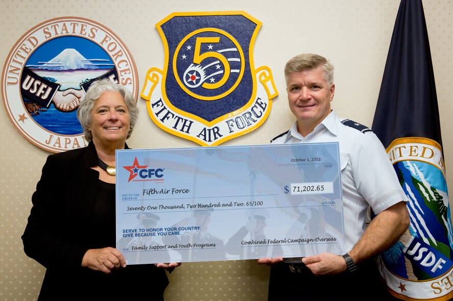 YOKOTA AIR BASE, Japan -- Renee Acosta, president and CEO of Global Impact, the managing company of Combined Federal Campaign-Overseas, presents Brig. Gen. Jerry Harris Jr., 5th Air Force vice commander, a $71,202 check for family support and youth programs, Oct. 1, 2012 at Yokota Air Base, Japan. In 2011, more than 4,000 service members from 5th AF contributed more than $917,000 for the CFC-O. (U.S. Air Force photo by Osakabe Yasuo)