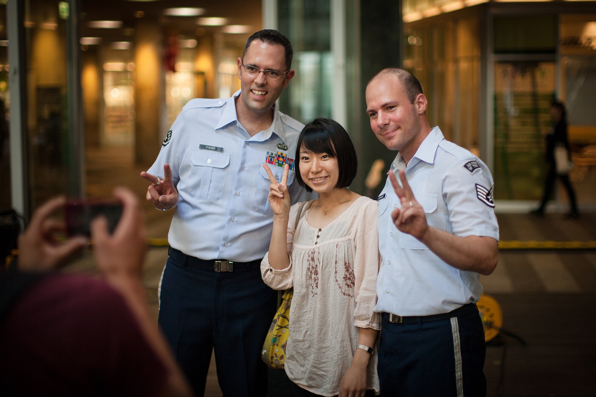 SAITAMA, Japan -- Staff Sgt. Geoff Fisher, Band of the Pacific-Asia vocalist, and Staff Sgt. Mike Schmaus, Band of the Pacific-Asia bassist, pose for a photo with a Japanese woman at the Saitama Super Arena Keyaki Square, Saitama, Japan on Oct. 2, 2012. Many people expressed excitement to have a photograph taken with Pacific Trends after the concert. (U.S. Air Force photo/Staff Sgt. Josh Voyles)