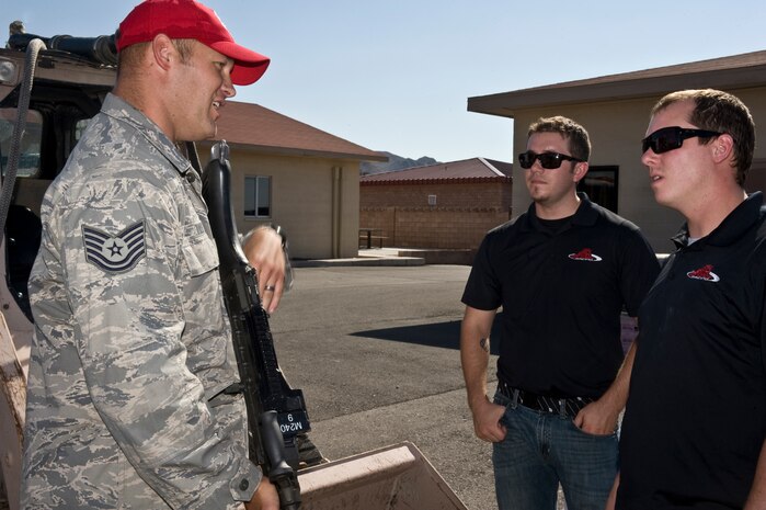 Tech. Sgt. Joshua Tully, 820th RED HORSE noncommissioned officer in charge of airborne fire emergency services, shows Red Horse Racing's Dick Claveloux, mechanic, and Tyler Jones, truck chief, an M240 machine gun during the visit to the 820th RED HORSE compound Sept. 27, 2012, at Nellis Air Force Base, Nev.  Airmen of the 820th RED HORSE conduct forward operating base construction, force protection build-up, and infrastructure assessment and repair. (U.S. Air Force photo by Airman 1st Class Matthew Lancaster)