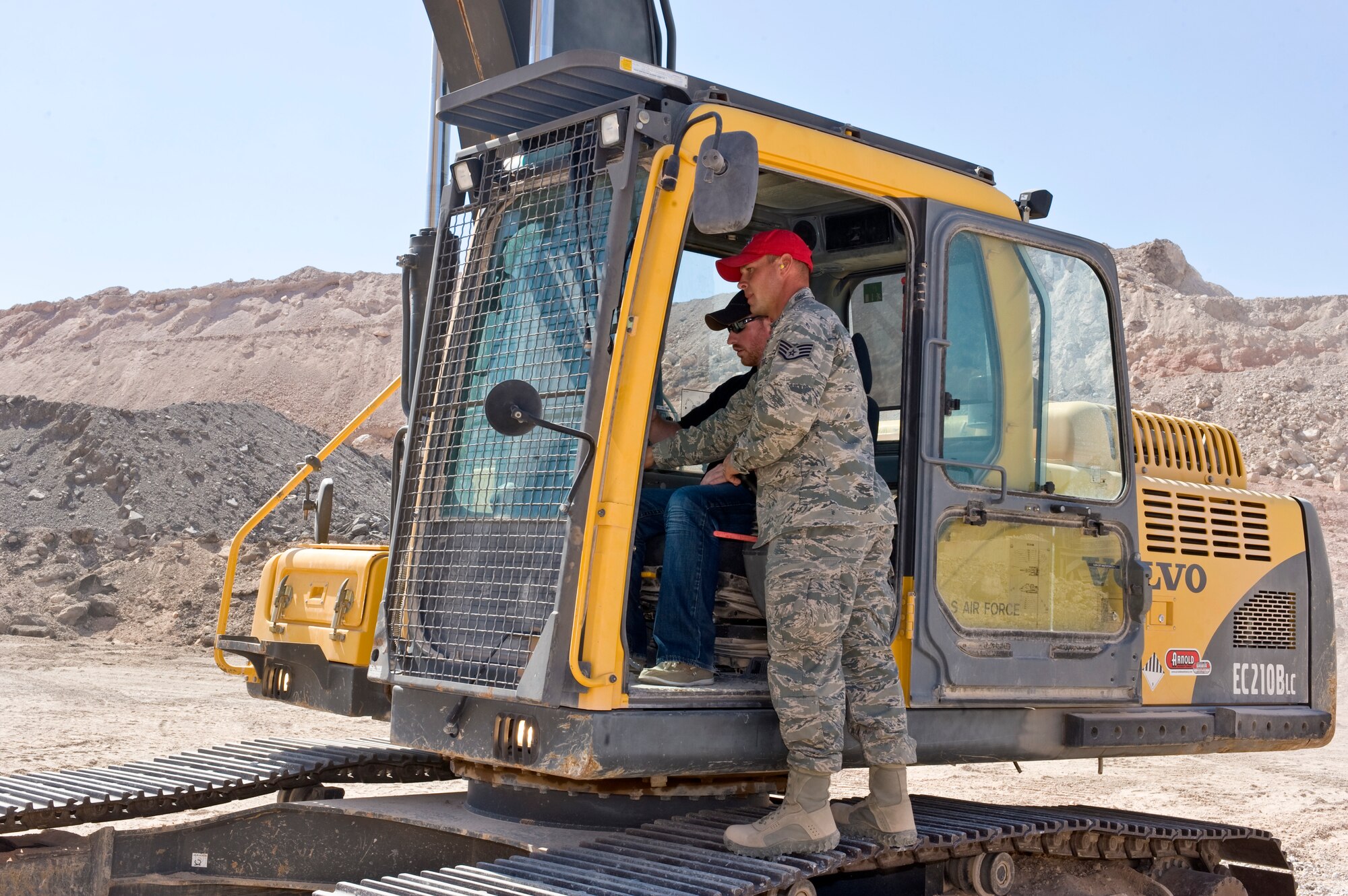 Staff Sgt. Drew Huffman, 820th RED HORSE airborne pavement and equipments craftsman, shows Craig Noble, Red Horse Racing engineer, how to operate a Volvo Excavator during the visit to the 820th RED HORSE compound Sept. 27, 2012, at Nellis Air Force Base, Nev.  Everyone on the Red Horse Racing team got a chance to operate the heavy equipment. (U.S. Air Force photo by Airman 1st Class Matthew Lancaster)