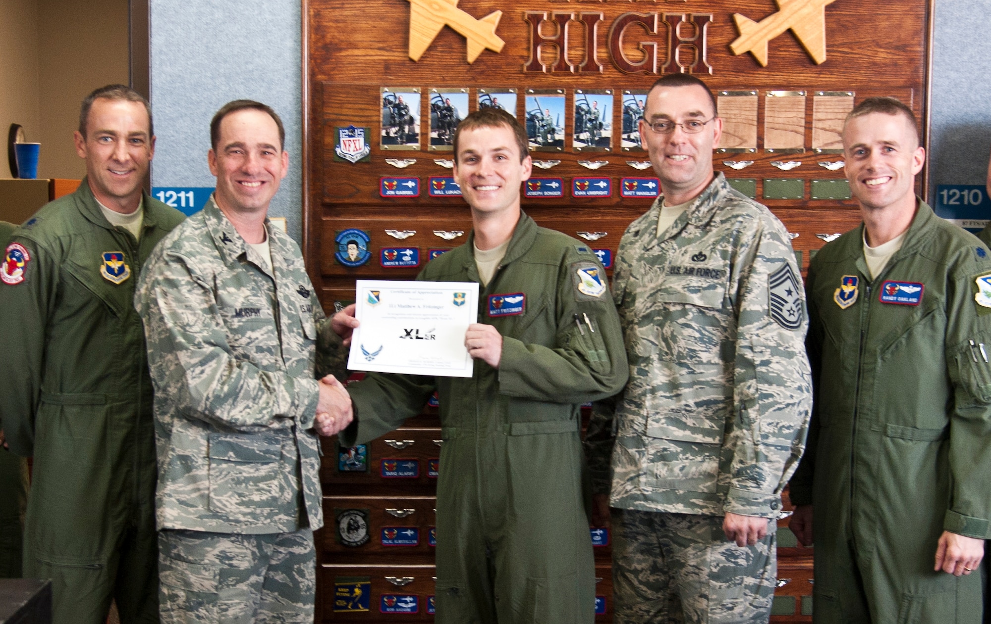First Lt. Matthew Fritzinger, 87th Flying Training Squadron instructor pilot, poses with Col. Tom Murphy, 47th Flying Training Wing commander, and Chief Master Sgt. Garry Berry, 47th FTW command chief, after being presented the XLer of the week award at Laughlin Air Force Base, Texas, Sept. 12, 2012. The XLer is a weekly award chosen by wing leadership and given to those who consistently make outstanding contributions to Laughlin and their unit. (U.S. Air Force photo/Airman 1st Class Nathan Maysonet)
