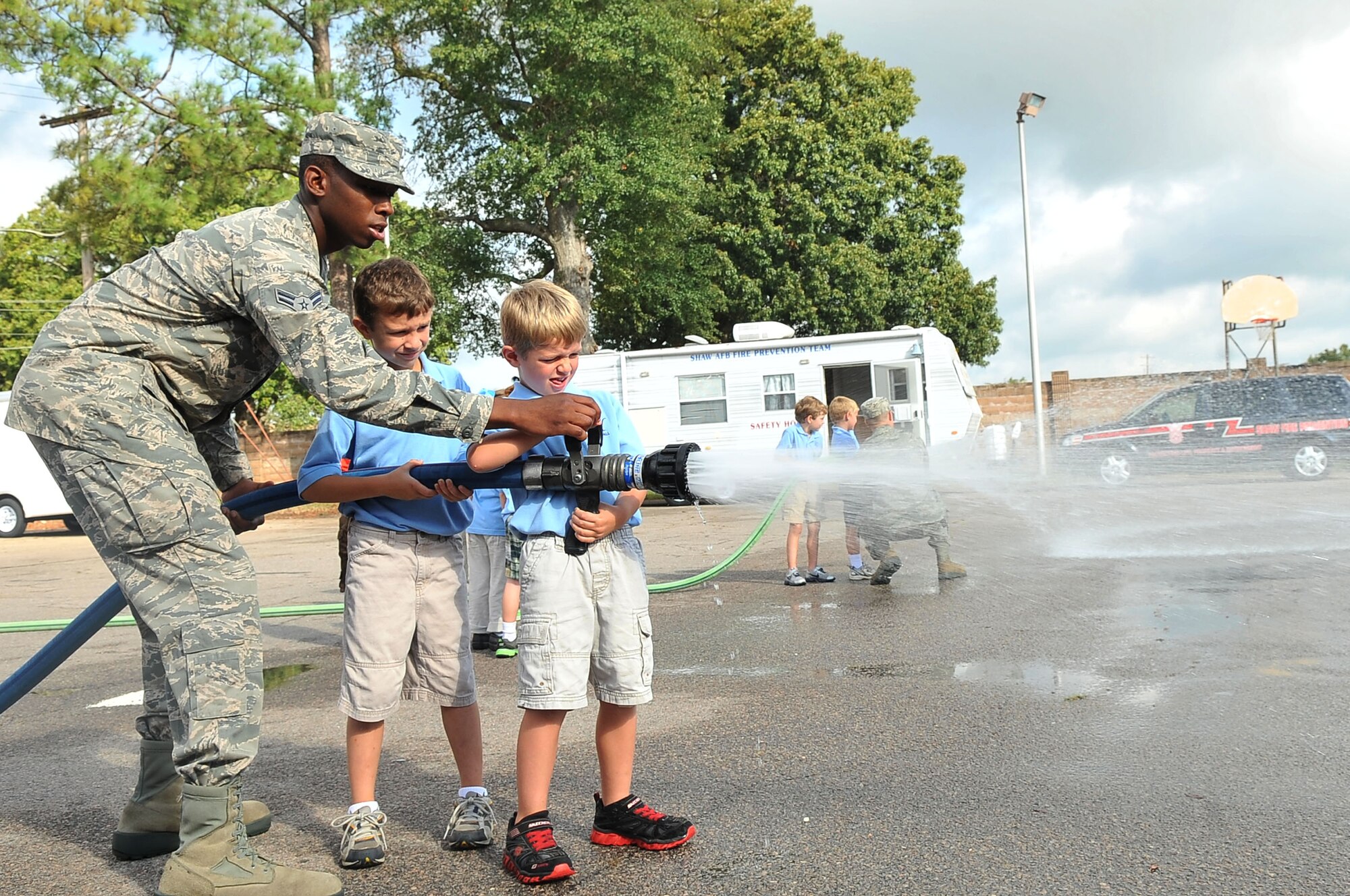 U.S. Air Force Airman 1st Class Harvey Cooper, 20th Civil Engineer Squadron firefighter, gives a group of kindergartners the opportunity to operate a fire hose during a fire department tour, Shaw Air Force Base, S.C., Oct. 2, 2012. The tour was given to children from Wilson Hall as October is fire prevention month. (U.S. Air Force photo by Airman 1st Class Ashley L. Gardner/ Released)