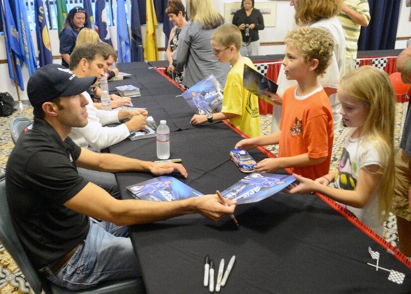 Aric Almirola, driver of the U.S. Air Force/Smithfield Foods No. 43 Chevy, hands an autographed picture to a child during the Race Week Social Sept. 28, 2012, at The Landings Club on Dover Air Force Base, Del. Attendees had the opportunity to get an autograph from or their picture taken with a driver, have their face painted , and eat free food. (U.S. Air Force photo by Tech. Sgt. Chuck Walker)