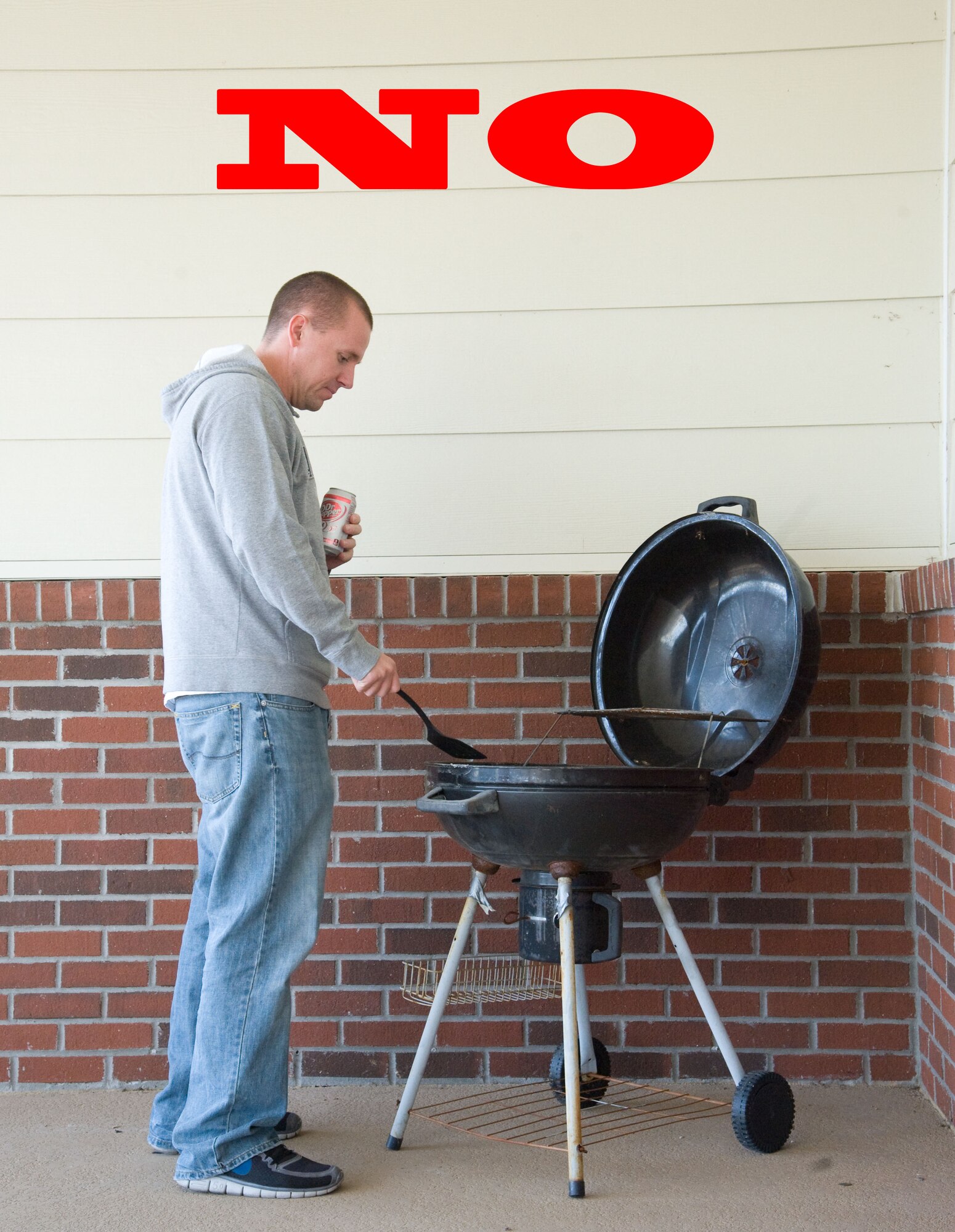 Staff Sgt. Robert Russell demonstrates improper grilling procedures Oct. 1, 2012, at Dover Air Force Base, Del. The National Fire Protection Association urges residents to keep grills at least 25 feet from the home, well away from deck railings and out from under eaves and patios. (U.S. Air Force photo illustration by Adrian R. Rowan)