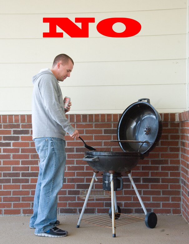 Staff Sgt. Robert Russell demonstrates improper grilling procedures Oct. 1, 2012, at Dover Air Force Base, Del. The National Fire Protection Association urges residents to keep grills at least 25 feet from the home, well away from deck railings and out from under eaves and patios. (U.S. Air Force photo illustration by Adrian R. Rowan)