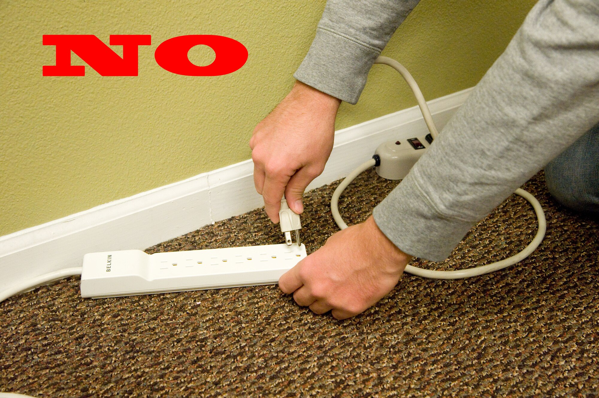 Staff Sgt. Robert Russell demonstrates “daisy-chaining,” plugging one surge protector into another, Oct. 1, 2012, at Dover Air Force Base, Del. The National Fire Protection Association says never to “daisy-chain” cords for more length, because it increases the risk of electrical fires. (U.S. Air Force photo illustration by Adrian R. Rowan)