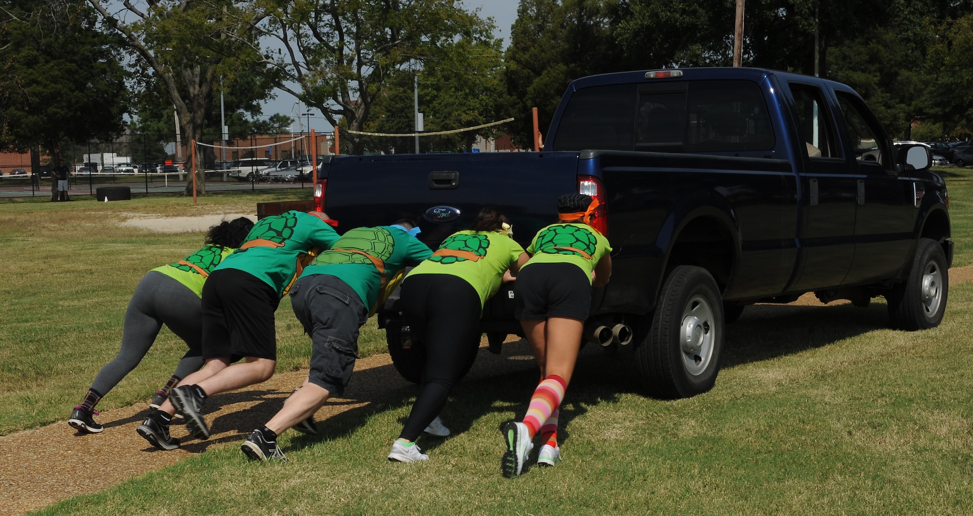 The "Cyber Ninja Turdles" push a truck toward a checkpoint during an expeditionary fitness challenge at Eagle Park, Langley Air Force Base, Va., Sept. 28, 2012. Teams performed various timed events, including litter carries, low crawling through sand and flipping a large tire. (U.S. Air Force photo by Airman 1st Class Teresa Aber/Released)