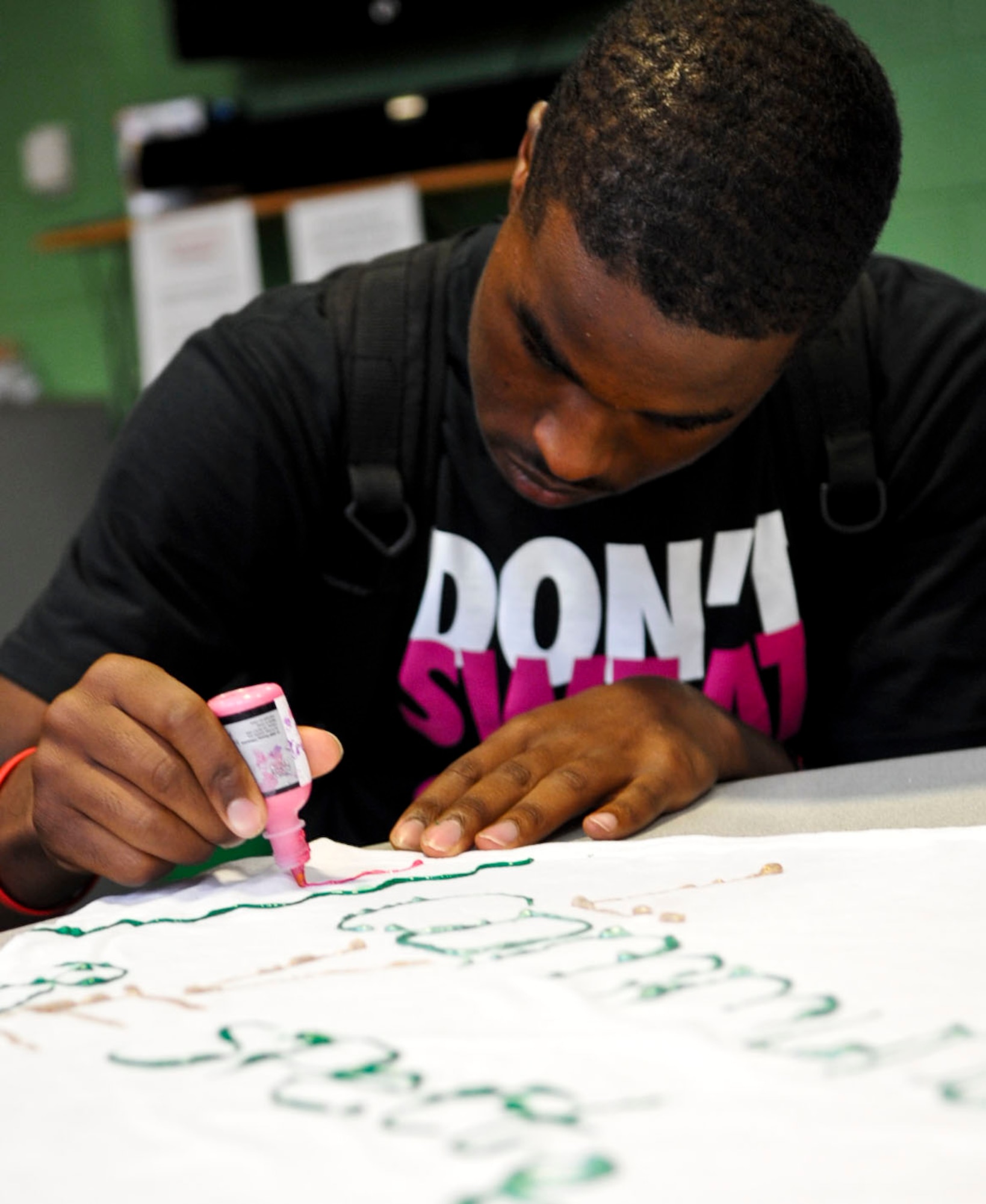 Alex Jasper, 16, decorates a T-shirt with positive messages during an after-school youth program at Fort Eustis, Va., Oct. 1, 2012. Teens at the Youth Center painted shirts as part of the installation's Domestic Violence Awareness Month activities, which focuses on stopping violence and offering support for the abused. (U.S. Air Force photo by Staff Sgt. Wesley Farnsworth/Released)