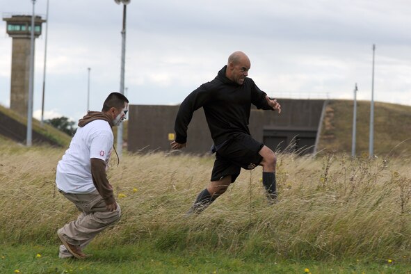 RAF MOLESWORTH, United Kingdom – Raymond Cummings escapes from a zombie through tall grass at the finish line of the Zombie Survival 5K Run held by the 501st Combat Support Wing Emergency Management Flight Sept. 28 on RAF Molesworth, United Kingdom. The run was held in support of National Preparedness Month (U.S. Air Force photo by Master Sgt. John Barton)