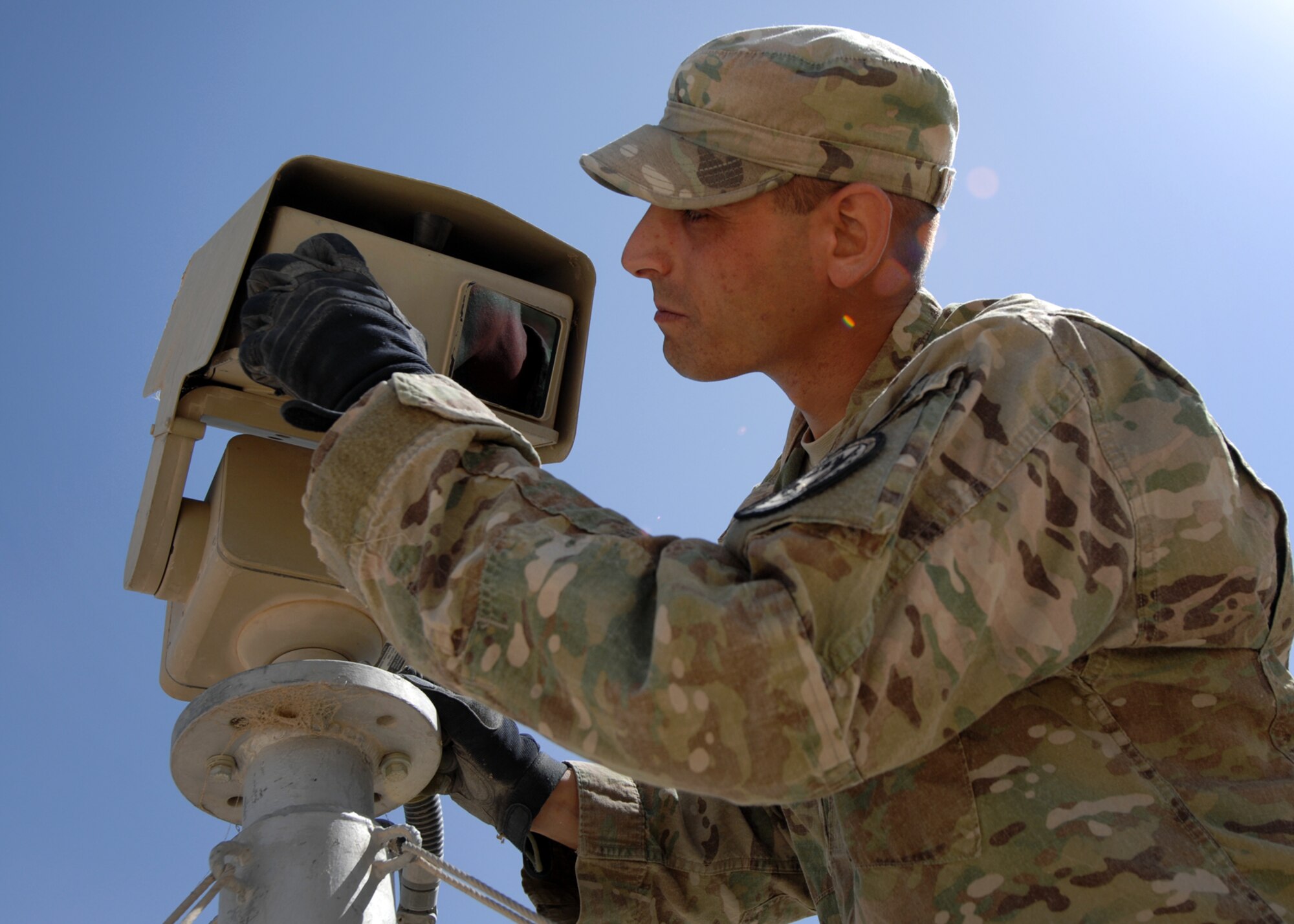 U.S. Air Force Tech Sgt. Joseph Cavallaro, 451st Expeditionary Security Forces Squadron tactical automated security system administrator, cleans a long range thermal imager lens atop a tower at KAF. (U.S. Air Force photo/Master Sgt. Russell Martin/RELEASED)