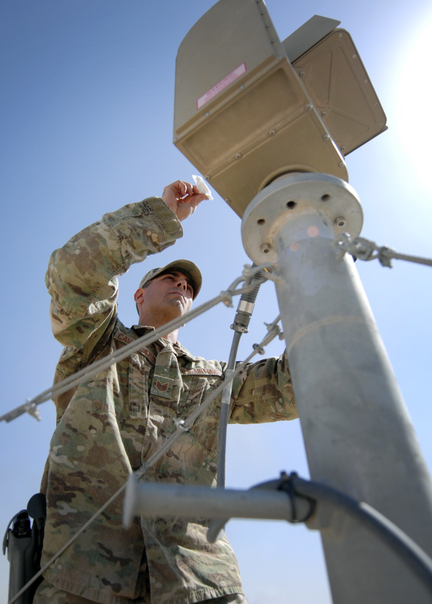 U.S. Air Force Tech Sgt. Joseph Cavallaro, 451st Expeditionary Security Forces Squadron tactical automated security system administrator, cleans a long range thermal imager lens atop a tower at KAF. (U.S. Air Force photo/Master Sgt. Russell Martin/RELEASED)