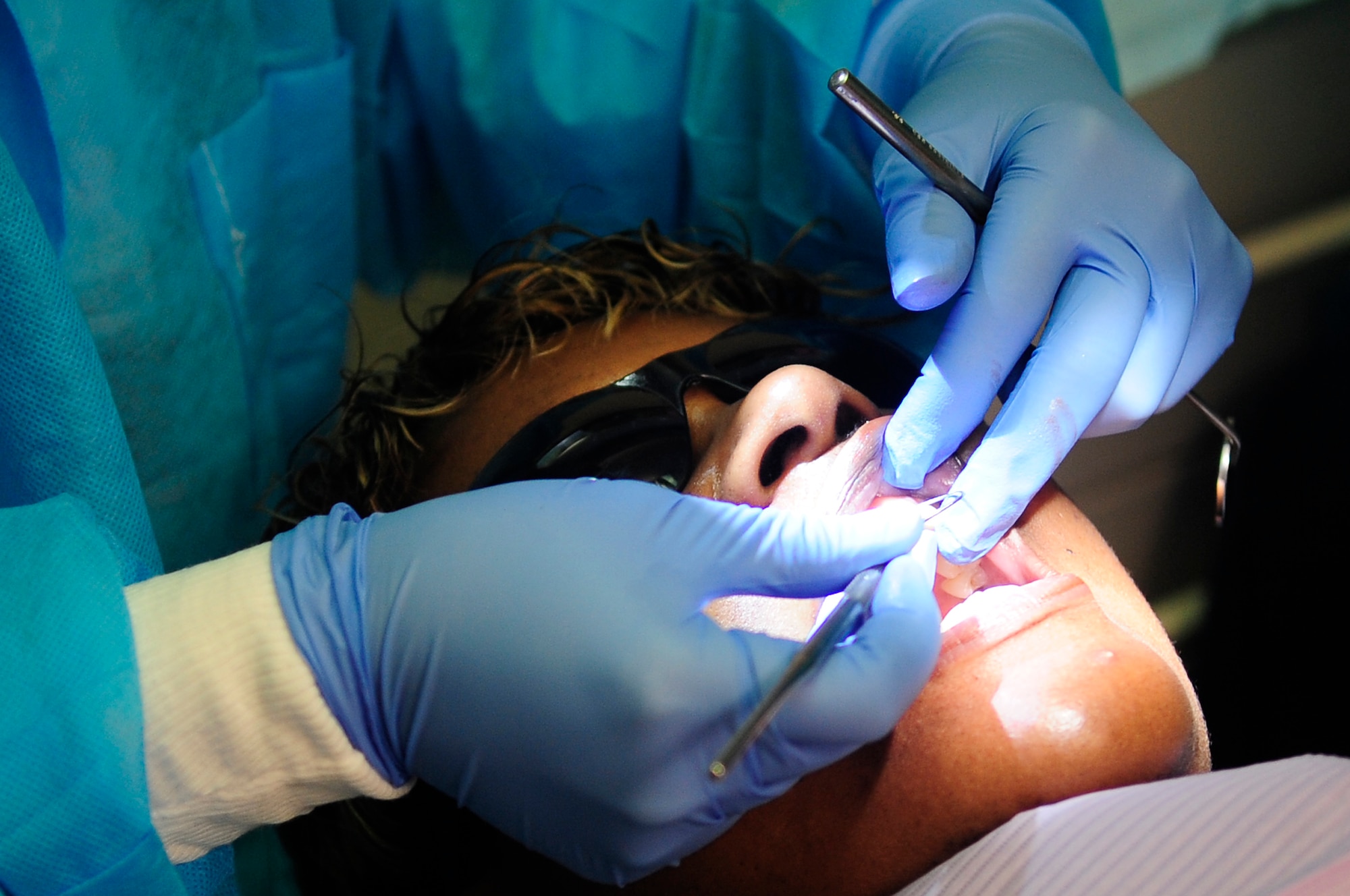 U.S. Air Force Capt. Jennilyn Estell, 20th Dental Squadron doctor of medical dentistry, begins to clean the teeth of the patient, Tanya Maisonet, during a training exercise for the Red Cross Volunteer Dental Assistance Program, Shaw Air Force Base, S.C., Sept. 24, 2012. The Red Cross Dental Assistance Program offers dental education to military dependents and spouses, with over 900 hours of both classroom and hands-on training. (U.S. Air Force photo by Airman Hunter Brady/Released) 
