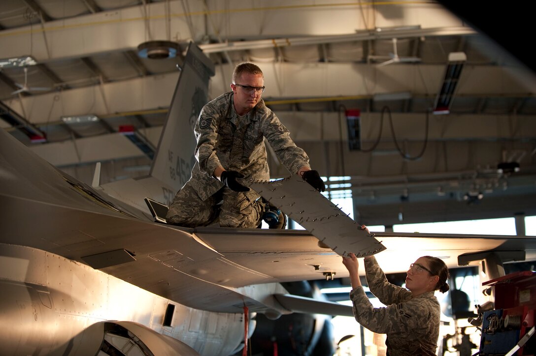 Two airmen simulate a panel being removed from an F-16 Fighting Falcon during an Air National Guard commercial shoot September 28, 2012 in Peoria, Ill.