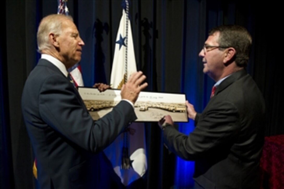 Deputy Secretary of Defense Ashton Carter, right, presents Vice President Joseph Biden a photograph of Mine Resistant Ambush Protected (MRAP) vehicles after the MRAP transition ceremony at the Pentagon on Oct. 1, 2012.  The ceremony marks the start of the transition of the MRAP Joint Program Office from the Marine Corps to the Army and the formal establishment of an MRAP Program of Record within each service.   