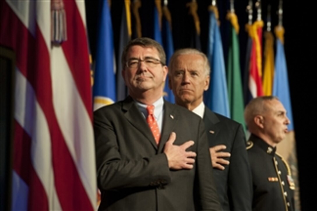 Deputy Secretary of Defense Ashton Carter and Vice President Joseph Biden stand for the singing of the national anthem at a transition ceremony for the Mine Resistant Ambush Protected (MRAP) vehicles program at the Pentagon on Oct. 1, 2012.  The ceremony marks the start of the transition of the MRAP Joint Program Office from the Marine Corps to the Army and the formal establishment of an MRAP Program of Record within each service.   