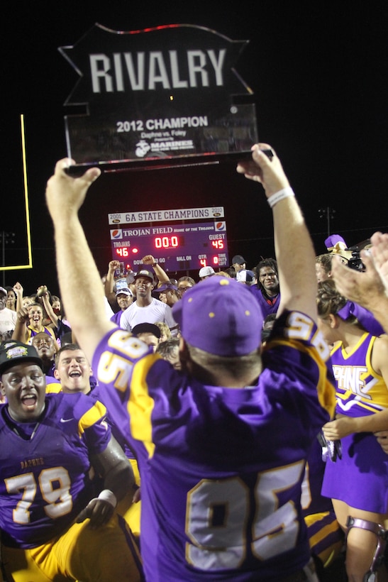 A member of the Daphne High School Trojans football team holds up the Great American Rivalry Series trophy after their overtime win against the Foley High School Lions September 14, 2012. The Trojans came back from a 14 point deficit in the fourth quarter to send the game into overtime where the game was decided by a field goal.