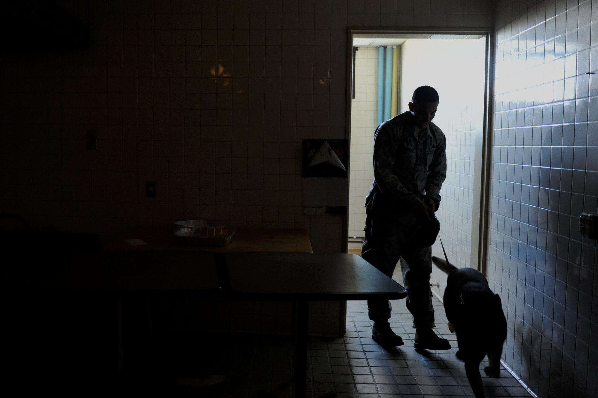 U.S. Air Force Staff Sgt. Ralph Rodriquez Hernandez, 18th Security Forces Squadron military working dog handler, walks out of a room after searching for drug paraphernalia with military working dog Benny on Kadena Air Base, Japan, Oct. 2, 2012. Any time the squadron receives new MWD teams, they must go through a series of training scenarios in order to be allowed to patrol the base for real-world scenarios. (U.S. Air Force photo/Airman 1st Class Brooke P. Beers)