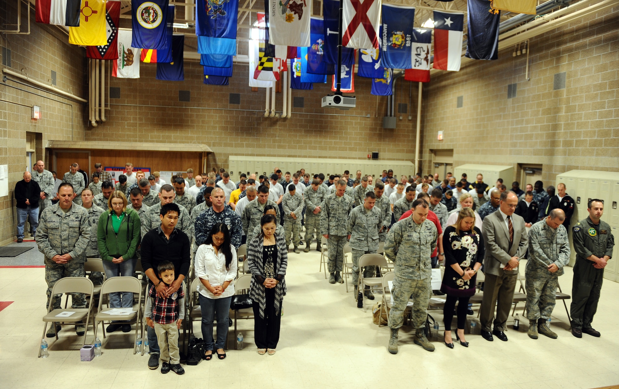 The men and women of the 55th Security Forces Squadron stand together in prayer at the conclusion of the annual Fallen Defenders and Master at Arms Dedication Ceremony held in the guard mount room of the 55th SFS building Offutt Air Force Base, Neb., Sept. 28.  Family members and coworkers were also in attendance to pay their respects to their fallen loved ones.  (U.S. Air Force photo by Josh Plueger/Released)