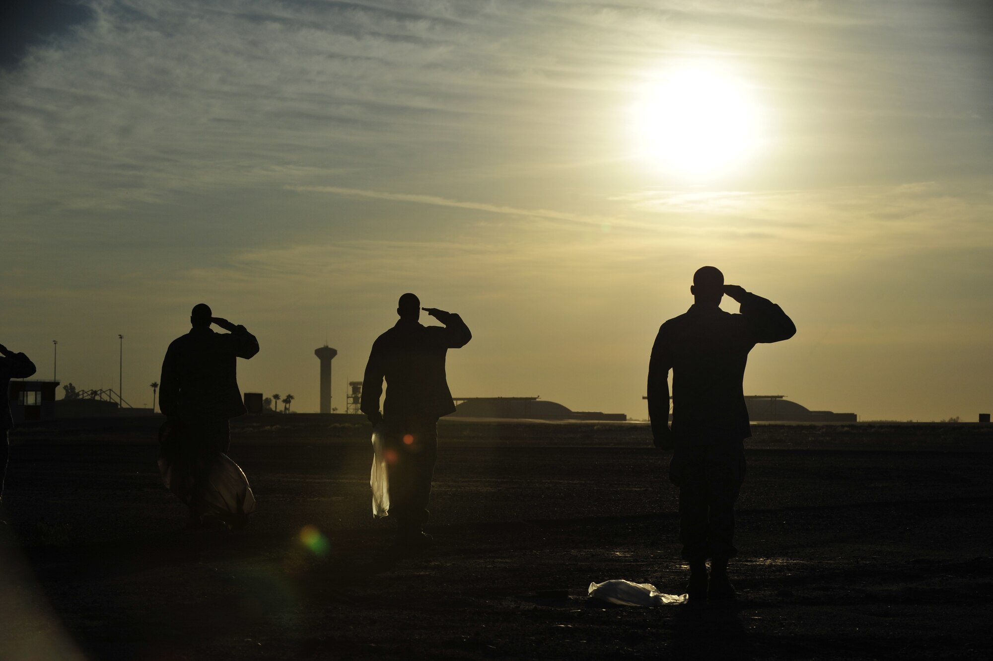 Airmen at Luke Air Force Base, Ariz., stop to salute as reveille plays before continuing to look for foreign object debris during a Wing FOD walk, Sept. 27, 2012. By performing a FOD walk, the Airmen help to ensure that the flightline is free of debris that may cause damage to the F-16 Fighting Falcons that fly at Luke. (U.S. Air Force photo by Staff Sgt. Jason Colbert)
