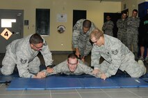 HANSCOM AIR FORCE BASE, Mass. - Staff Sgts. Matthew McFarland (left) and Michael Compitiello hold down Airman 1st Class Robert Stevens as Tech. Sgt. Scott Roy tases him during a 66th Security Forces Squadron training event Sept. 25. The training allowed the Airmen to learn about the neuro-muscular incapacitation device, which allows security forces to expand the use of force option while minimizing fatalities and permanent injury to personnel. (U.S. Air Force photo by Linda LaBonte Britt)