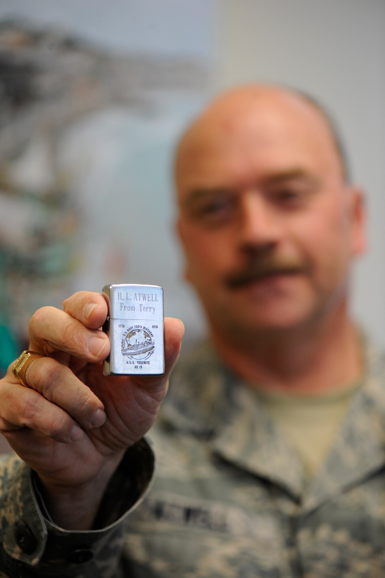 MSgt. Terry Atwell holds a cigarette lighter that he gave to his late father, Harold Atwell, in 1976. The lighter features the insignia of the USS Yosemite, a Navy destroyer on which the younger Atwell was serving as part of the crew at the time. The lighter was lost in a field sometime prior to 1994 when Harold Atwell died. A stranger recently found the lighter and returned it to the son, sparking a flood of memories. Atwell holds the lighter in his office at Selfridge Air National Guard Base, Mich., Oct. 2, 2012. (Air National Guard photo by John S. Swanson)