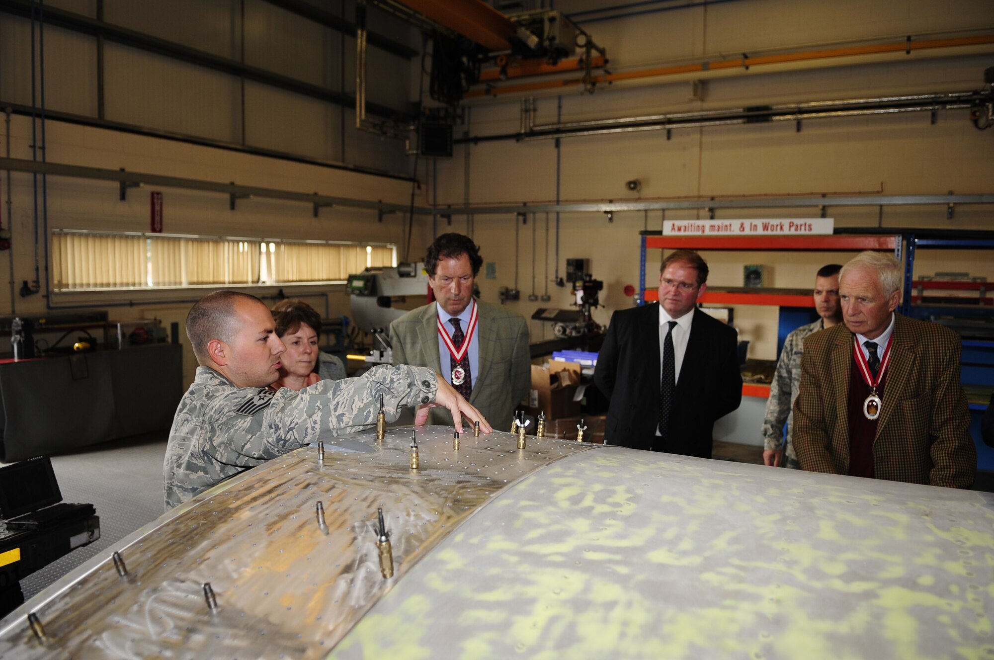 RAF MILDENHALL, England – On left, Tech Sgt. Timothy Farmkis, 100th Maintenance Squadron aircraft structural maintenance craftsman, briefs the High Sheriffs of Suffolk, Norfolk and Cambridgeshire, England and their spouses on the mission and capabilities of aircraft structural maintenance during a base tour of RAF Mildenhall and RAF Lakenheath, Sept. 25, 2012. Farmis walked the High Sheriffs and their spouses through the process of repairing old aircraft parts that are no longer manufactured. (U.S. Air Force photo/Senior Airman Ethan Morgan)
