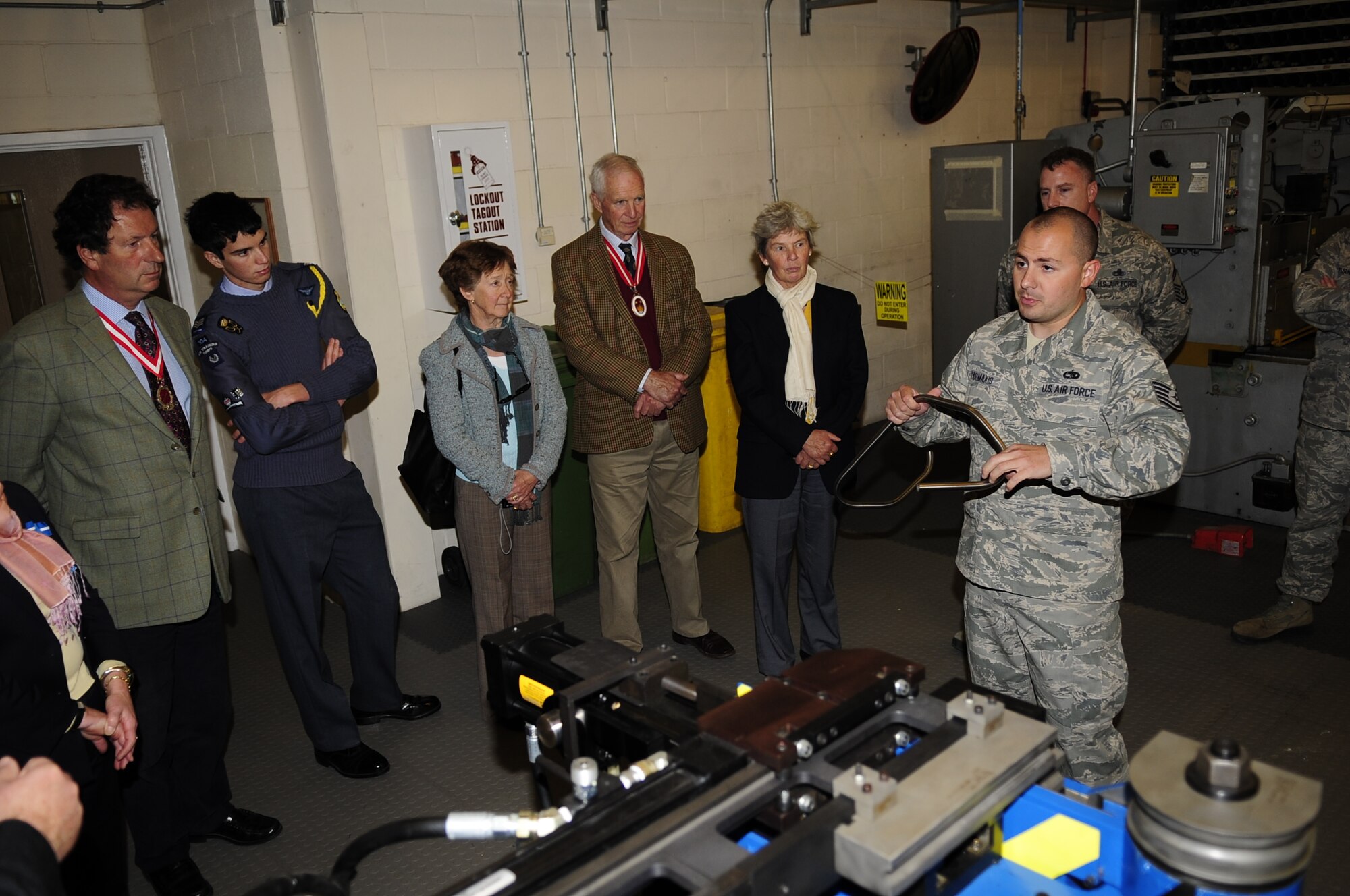 RAF MILDENHALL, England – On right, Tech Sgt. Timothy Farmkis, 100th Maintenance Squadron aircraft structural maintenance craftsman, briefs the High Sheriffs of Suffolk, Norfolk and Cambridgeshire, England and their spouses on the mission and capabilities of aircraft structural maintenance during a base tour of RAF Mildenhall and RAF Lakenheath, Sept. 25, 2012. Farmkis explained how the specialized equipment that they use better achieves the mission. (U.S. Air Force photo/Senior Airman Ethan Morgan)