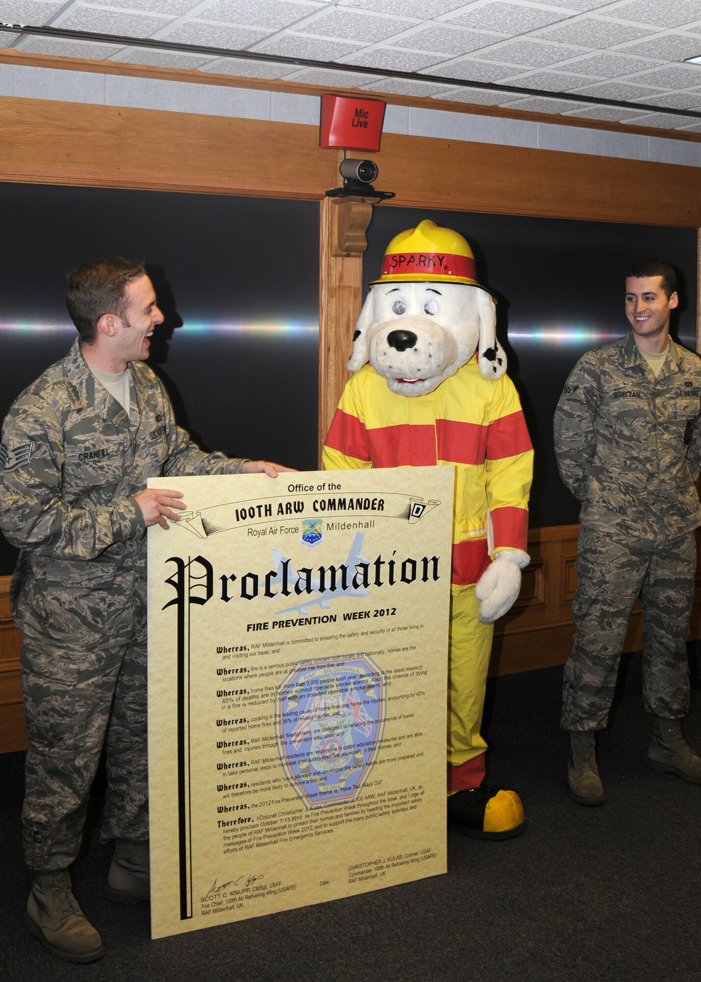 From left, Staff Sgt. Andrew Cranfill, Sparky the Fire Dog and Airman Kevin Brittan, all 100th Civil Engineer Squadron firefighters, brief on upcoming for Fire Prevention Week events Oct. 3, 2012, during the weekly wing commander’s meeting at RAF Mildenhall, England. Fire Prevention Week is held annually and is meant to provide continued education for service members and their families on preventing and responding to fires. (U.S. Air Force photo by Tech. Sgt. Neal X. Joiner/Released) 