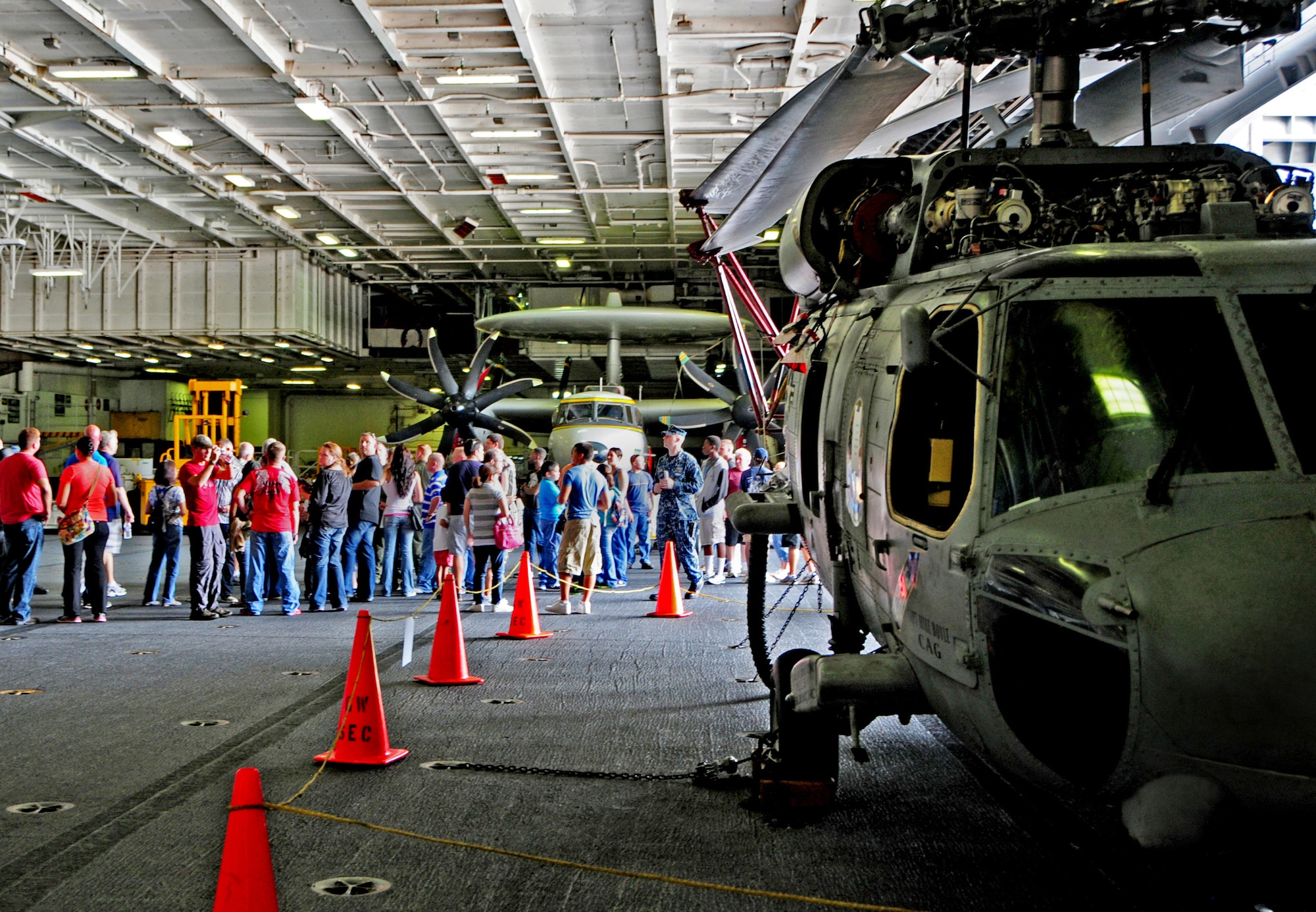 NAVAL BASE, Guam – Tour groups congregate at the main hangar deck of the USS George Washington (CVN 73) in order to board the lift to the flight deck here, Sept. 22. During the tour, Airmen and their families were able to see Naval aircraft up close while crewmembers provided the tour groups with information on the aircraft and the carrier’s historical background. (U.S. Air Force photo by Airman 1st Class Marianique Santos/Released)