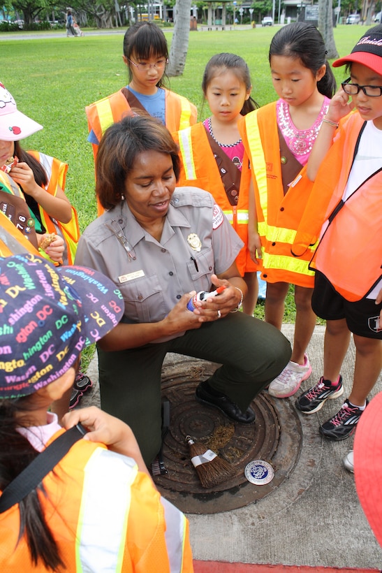 Angela Jones, head park ranger for the Corps’ Regional Visitor Center, demonstrates how to install a storm drain marker for Girl Scout Brownie Troop 276 as part of National Public Lands Day, Sept. 29. The drain markers remind people to dump no waste since the water drains to the ocean. More than 60 volunteers scoured Fort DeRussy in Waikiki, picking up trash and installing storm drain markers as part of the national event. The Corps’ Regional Visitor Center coordinated the event which was supported by Corps employees, Iolani School’s Brownie Troop 276 and Punahou Junior ROTC cadets. 