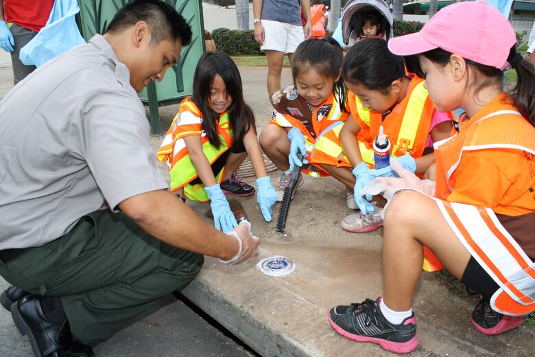 Park Ranger Don Espaniola of the Corps’ Regional Visitor Center, helps Girl Scout Brownie Troop 276 install a storm drain marker as part of National Public Lands Day Sept. 29.   The drain markers remind people to dump no waste since the water drains to the ocean. More than 60 volunteers scoured Fort DeRussy in Waikiki, picking up trash and installing storm drain markers as part of the national event. The Corps’ Regional Visitor Center coordinated the event which was supported by Corps employees, Iolani School’s Brownie Troop 276 and Punahou Junior ROTC cadets.