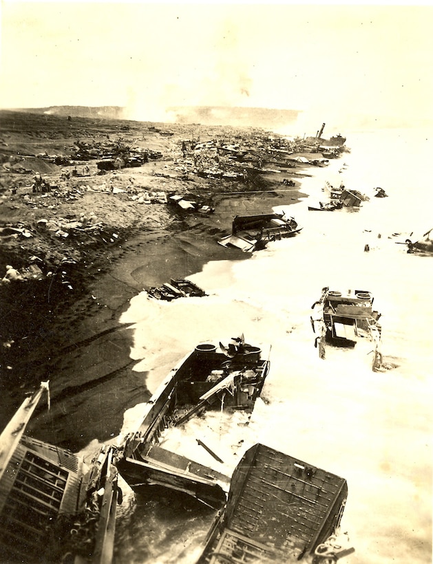 Aftermath of amphibious assault on Iwo Jima, wrecked landing craft and equipment are spread over most of the beach.