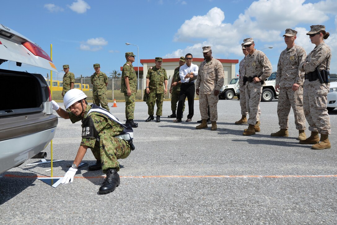 Japan Ground Self-Defense Force military policemen explain their accident response procedures to Marine MPs during a bilateral training event at Camp Foster Oct. 2. The training included both a classroom session and live demonstrations of investigation procedures at a staged accident scene by the JGSDF and Marine MPs. The JGSDF MPs are with the 136th Western District Military Police, Western Army Military Police, MP Headquarters. The Marine MPs are with the Provost Marshal’s Office, Headquarters and Service Battalion, Marine Corps Base Camp Butler. 